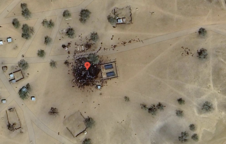 Satellite image of a waterhole in dry terrain with many dark dots – most likely animals, not dead people as claimed.