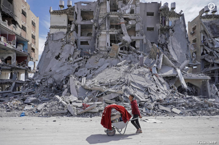 Ein Mann schiebt eine Schubkarre mit Habseligkeiten an zerstörten Wohnhäusern in Gaza vorbei.